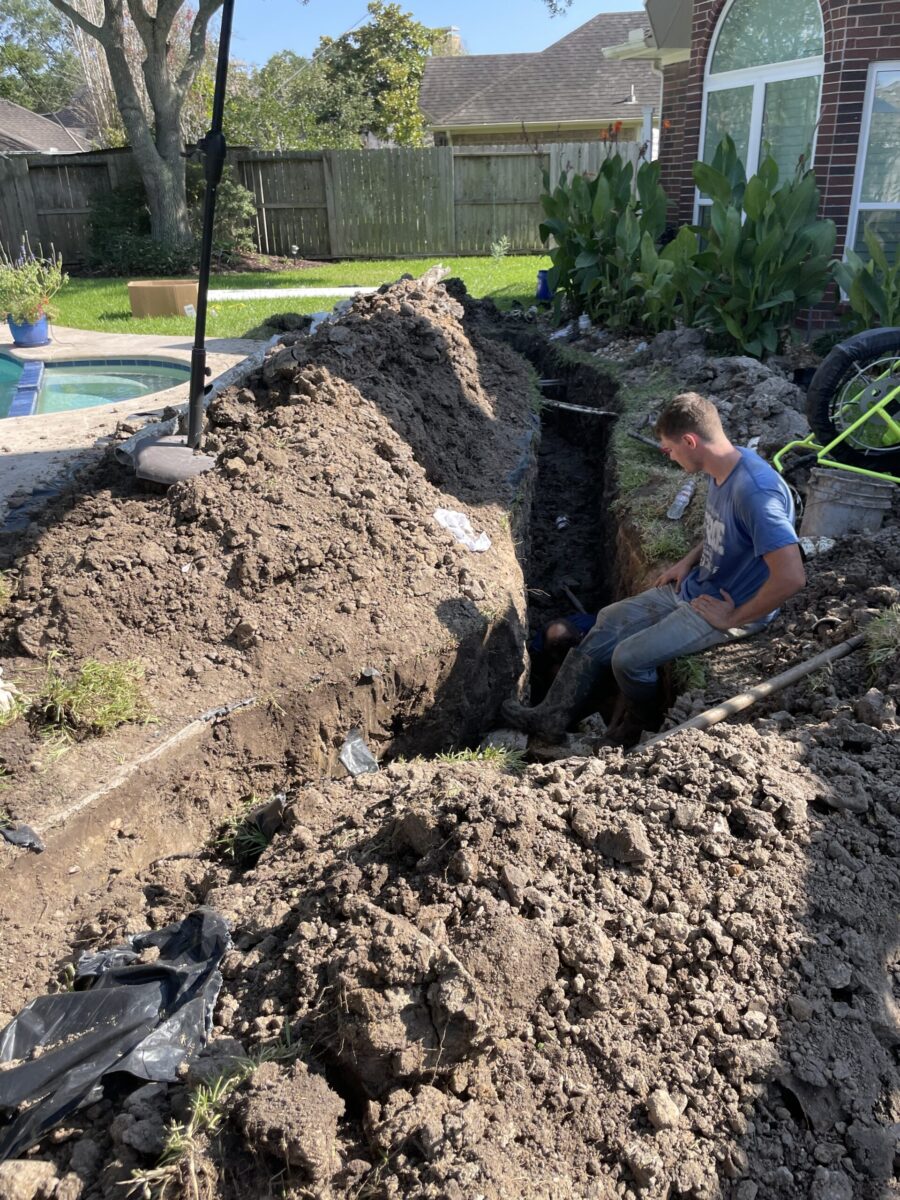 A man is digging a hole in a backyard.