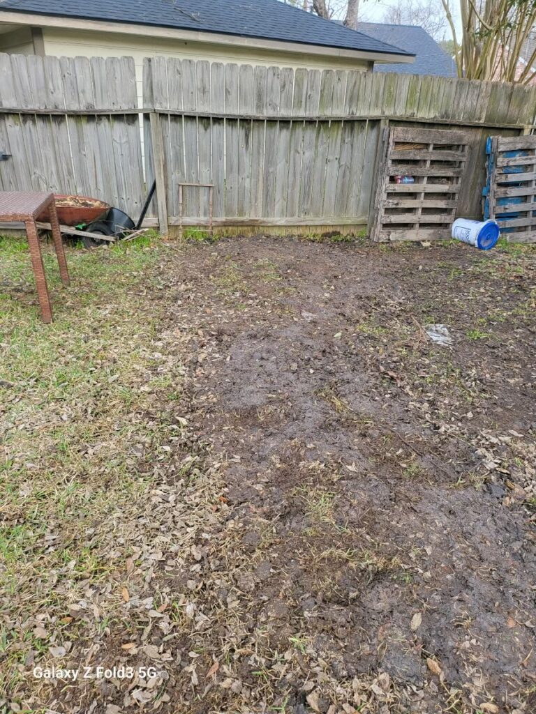 A muddy backyard with a wooden fence.